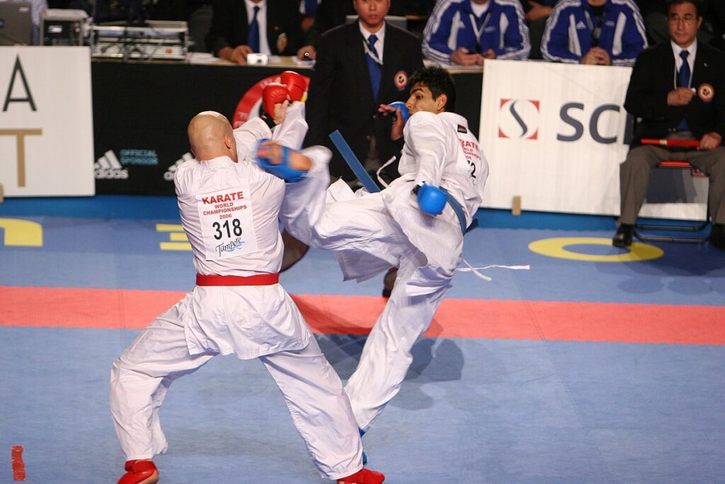 A karateka kicking his opponent with his foot